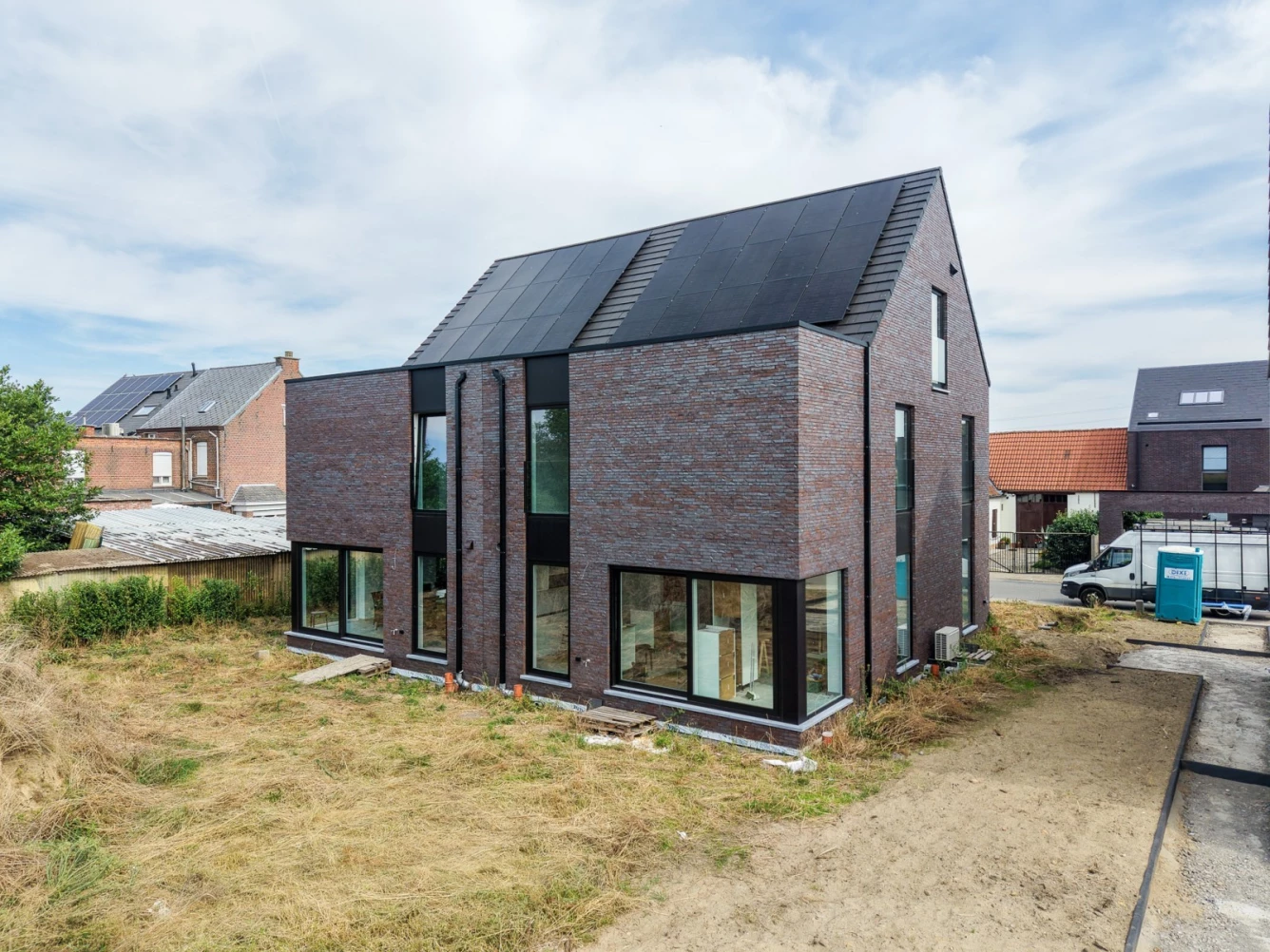 halfopen woning in puurs met donkere gevelsteen en zwarte ramen met veel lichtinval